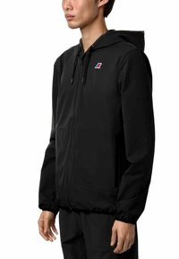 Felpa nera con zip e cappuccio regolabile, caratterizzata da un sottile dettaglio del logo, tasche frontali e una finitura liscia e texture.