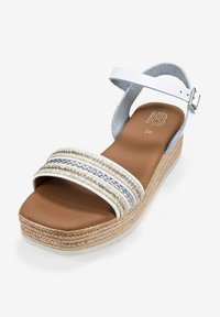 Sandalia cuña blanca con diseño de tira trenzada que presenta acentos en beige y plata. Suela de yute texturizada. Talla 36 marcada en la plantilla.