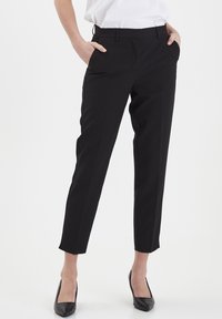 Pantaloni neri su misura con taglio dritto, tasche e una texture liscia. Presentano un fronte piatto e una lunghezza leggermente accorciata.