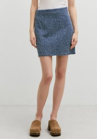 Gehaakte minirok in blauw met een gestructureerd, geribbeld patroon en een elastische tailleband. Gecombineerd met tan platformklompen met zilveren studs.