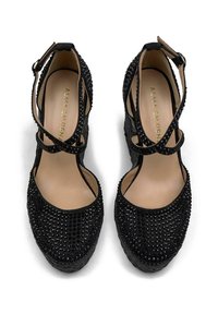 Chaussures à plateforme noires avec un design texturé, ornées de strass noirs, dotées de brides de cheville réglables et d'un bout arrondi.