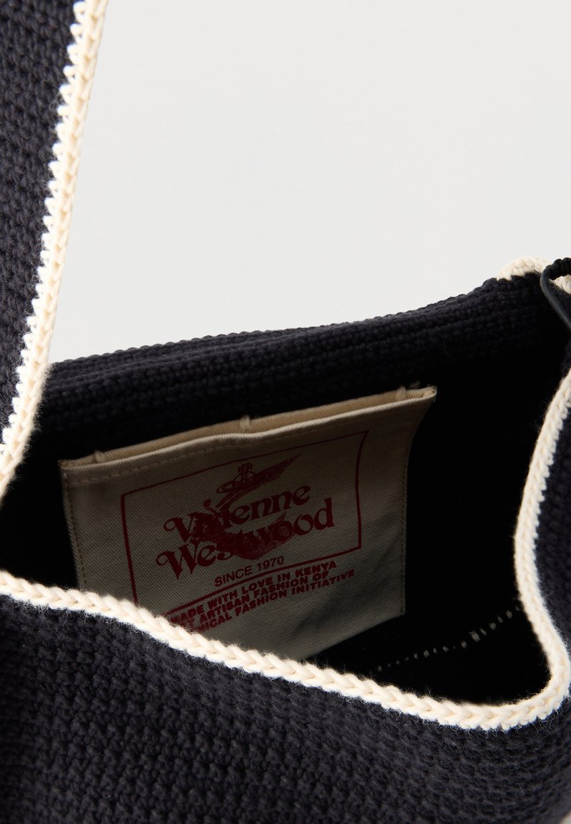 Close-up of a black crocheted bag with white trim showing an inner label reading "Vivienne Westwood" in red text.