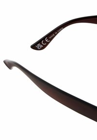 Lunettes de soleil brunes avec des branches incurvées et brillantes. Le texte imprimé comprend "CE" et "FABRIQUÉ EN CHINE" près de la charnière.