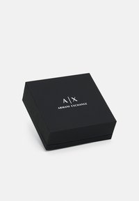 Crna kartonska kutija s poklopcem na šarkama, s glossy bijelim logotipom: "A|X ARMANI EXCHANGE" centriranim na vrhu.