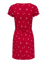 Robe rouge mi-genoux avec petits motifs floraux blancs, manches courtes retroussées, et ceinture nouée à la taille à l'arrière.