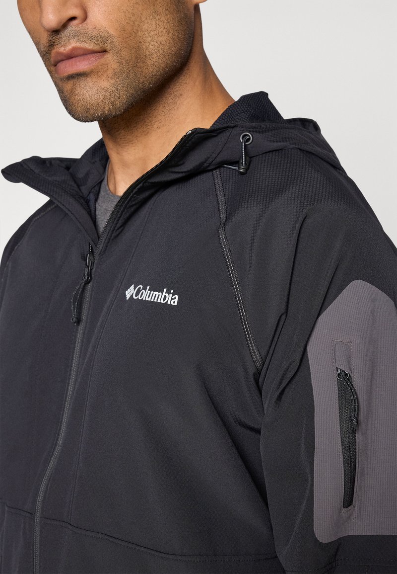 Czarna kurtka z kapturem, z zamkiem z przodu, z teksturowanej tkaniny i szarymi akcentami na rękawach. Posiada logo na piersi oraz funkcjonalną kieszeń.