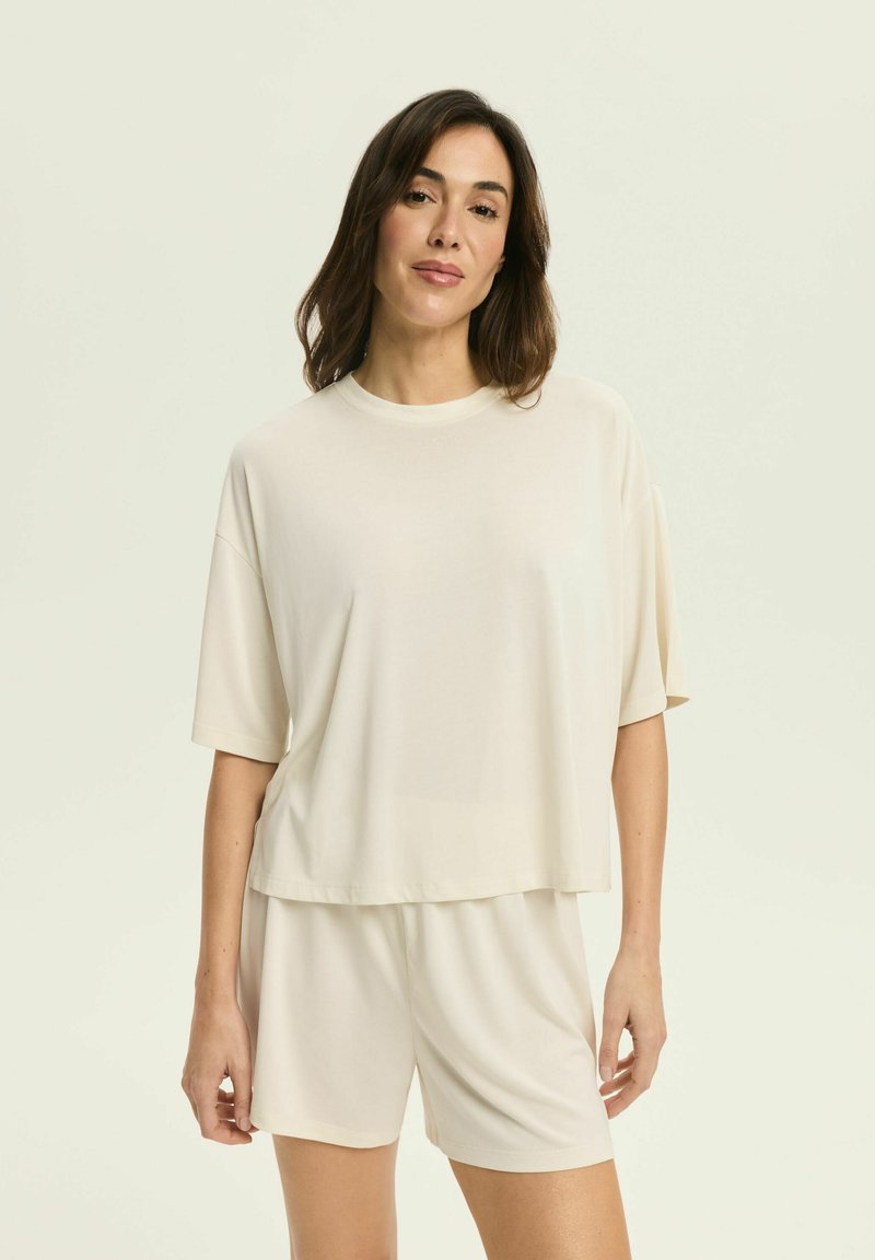 Light beige short-sleeve top with a round neckline, paired with matching shorts. Smooth texture, relaxed fit, and minimalistic design.