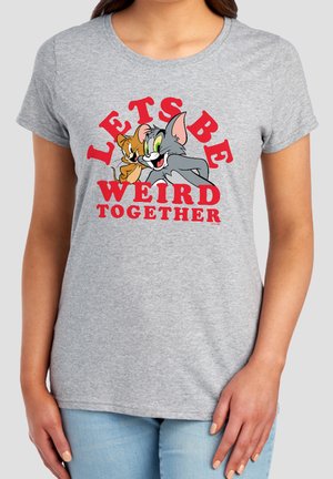 Woman wearing gray T-shirt with Tom and Jerry cartoon beside red text saying "LET'S BE WEIRD TOGETHER."