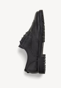 Scarpa in pelle nera con dettagli brogue, chiusura con lacci, punta arrotondata e suola in gomma testurizzata. La vista laterale mette in evidenza il design elegante.