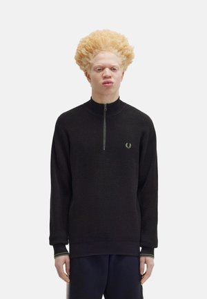 Maglione zip-up nero con tessuto texturizzato, colletto alto e polsini a coste, con un piccolo logo verde sul petto.
