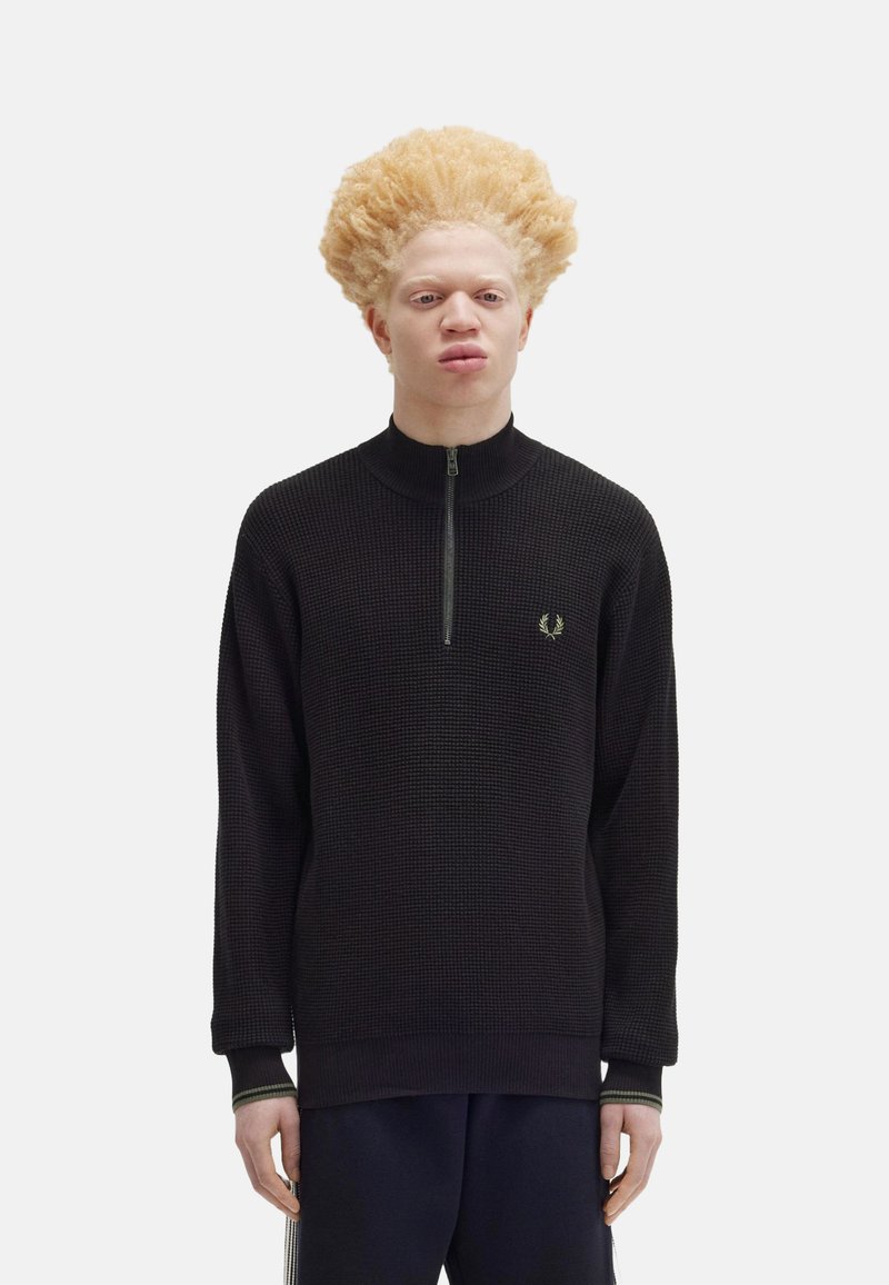Schwarzer Reißverschluss-Pullover aus strukturiertem Stoff, mit hohem Kragen und ribbed Bündchen, ausgestattet mit einem kleinen grünen Logo auf der Brust.