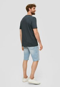 Korte, donkergrijze t-shirt met korte mouwen, gecombineerd met lichtblauwe spijkershorts en witte sneakers, gezien vanaf de achterkant. Gemaakt van katoen, casual pasvorm.