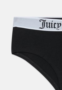 Czarna bielizna z szerokim białym pasem z napisem "Juicy" w gotyckim fontie, pokazana na jednolitym białym tle.
