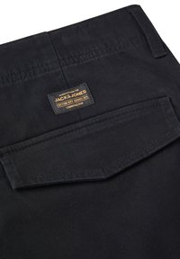 Czarne bawełniane spodnie z tylną kieszenią i tkaną metką z napisem "JACK & JONES". Materiał wydaje się gładki o matowym wykończeniu.