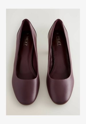 Balerini din piele sintetică burgundă, cu vârful rotund, textură netedă și toc mic. În interior au o talpă căptușită pentru confort.