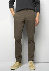 Bruine katoenen chino's met een gladde textuur, slim fit en zijzakken, gecombineerd met beige lage sneakers.
