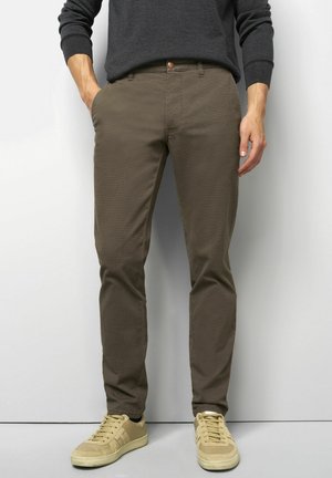 Bruine katoenen chino's met een gladde textuur, slim fit en zijzakken, gecombineerd met beige lage sneakers.
