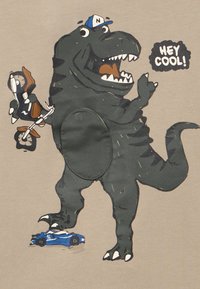 Κάρτουνα T-Rex που φοράει μπέιζμπολ καπέλο, κρατώντας ένα ποδήλατο, στέκεται πάνω σε μια πολτοποιημένη μπλε παιχνιδιάρικη αυτοκίνητο, λέγοντας «Ε! ΚΟΥΛ!» σε μπεζ φόντο.