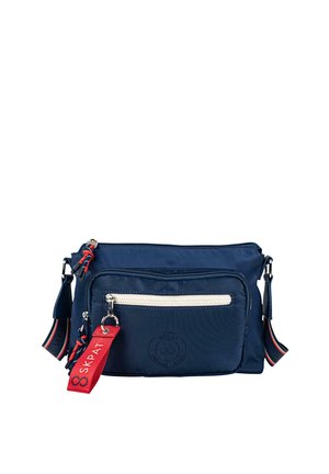Bolso bandolera de nylon azul marino con cremallera blanca, bolsillo frontal, etiqueta roja y detalles en negro. Cuenta con una correa ajustable y detalle de logo. Diseño compacto.