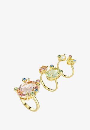 Trzy złote pierścionki z różnymi szlifami kamieni szlachetnych: duży różowy, jasny zielony oraz mniejsze, kolorowe akcenty. Gładka metalowa obrączka z misternymi osadzeniami.
