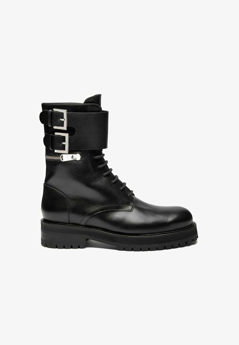 Stivale alla caviglia in pelle nera con suola spessa, cerniera laterale, lacci frontali e due fibbie argentate regolabili attorno alla parte superiore.
