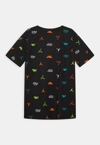 T-shirt di cotone nera con una stampa dispersa di logo Nike e Jordan in arancione, verde, blu e bianco, con maniche corte e scollatura rotonda.