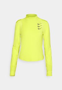 Haut de sport à manches longues de couleur jaune néon avec col montant et trois petits logos Nike en noir sur le coin supérieur droit de la poitrine.