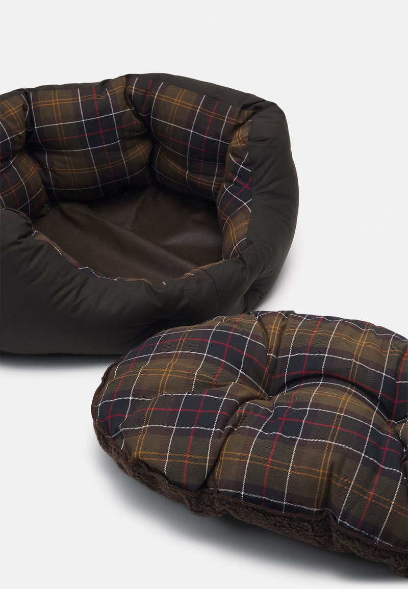 Cama de mascota redonda y acolchada con cojín extraíble que presenta un patrón de cuadros en marrón, negro y rojo sobre un fondo blanco.