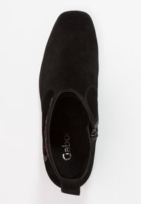 Czarne zamszowe botki za kostkę z kwadratowym noskiem, zamknięciem na zamek błyskawiczny oraz miękką podszewką wewnętrzną. Dekoracyjne czerwone przeszycia dodają kontrastu.