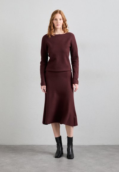 Bordeauxfarbenes Rippstrickpullover- und Rockset mit einem Bootsausschnitt, langen Ärmeln und figurbetonter Silhouette, kombiniert mit schwarzen Knöchelstiefeln.