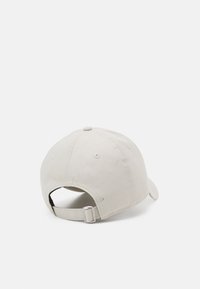 Beige Baumwoll-Baseballcap mit abgerundeter Krone, verstellbarem Riemen auf der Rückseite und sechs Belüftungslöchern. Weiche Textur und keine sichtbaren Logos.