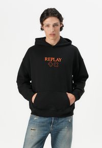 Czarna bluza z kapturem wykonana z miękkiego materiału, z pomarańczowym logo "REPLAY" i symbolami krzyża. Z przodu kangurza kieszeń, ściągacze przy mankietach.