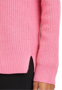 Rosa gestrickter Pullover mit geripptem Textur, gespaltenen Saumdetails und engen Bündchen. Der Stoff wirkt weich und warm.