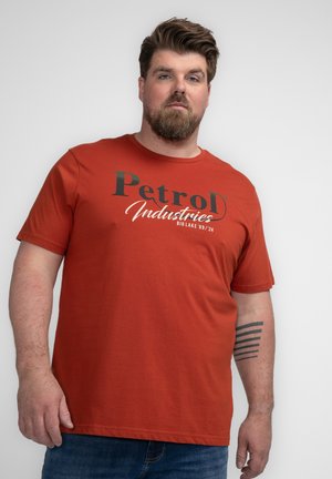 Camiseta de algodón color óxido con mangas cortas y escote redondo. Presenta un estampado gráfico audaz que dice "Petrol Industries".