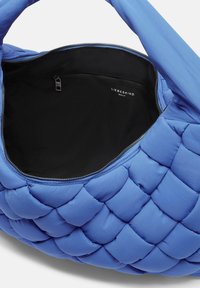 Niebieska torebka z pikowanej tkaniny o miękkiej fakturze, z zamykaną czarną kieszonką wewnętrzną. Widoczne logo wewnątrz.