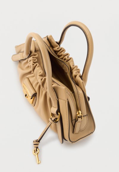 Μικρή τσάντα χειρός από μπεζ δέρμα με ραβδωτές πλευρές, διπλές λαβές, χρυσλό φερμουάρ και χρυσό μπρελόκ σε σχήμα κλειδιού προσαρτημένο σε δερμάτινο λουρί.