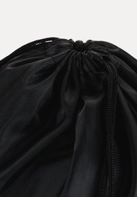 Nærbillede af en tæt sammenstrammet sort netpose med snøre, samlet top og flettede snore mod en hvid baggrund.