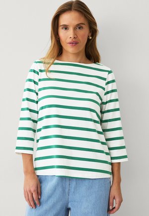 Gestreiftes Shirt in Weiß und Grün, aus weicher Baumwolle gefertigt. Verfügt über einen runden Ausschnitt und Dreiviertelärmel mit lockerer Passform.