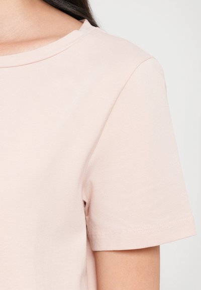 Light pink short-sleeve T-shirt with a ribbed crew neckline. Fabric appears soft and stretchy with a smooth texture. No visible patterns or accents.