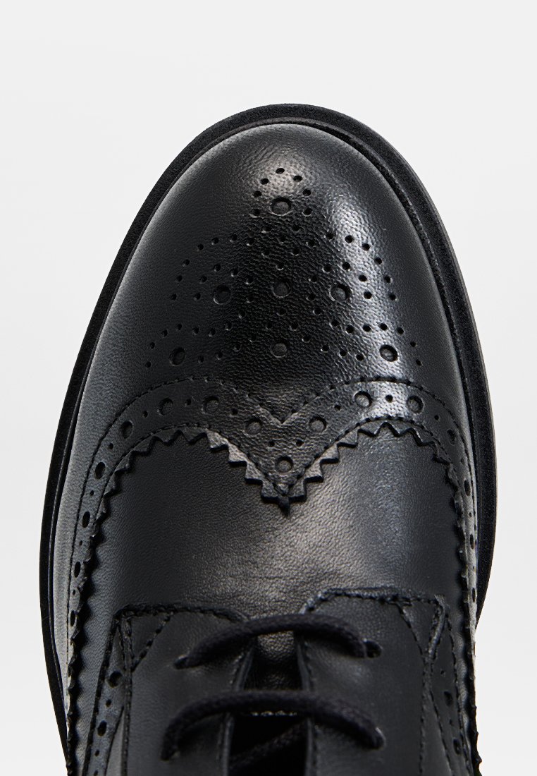 Scarpa da uomo in pelle nera con dettagli brogue, punta tonda e superficie texturizzata. Presenta una chiusura con lacci e perforazioni intricate.