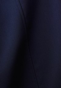 Tissu bleu marine foncé avec une couture visible courant verticalement, montrant une texture lisse et une légère ombre le long du pli.