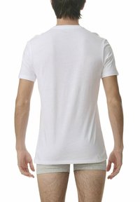 Biała koszulka z krótkim rękawem i okrągłym dekoltem, wykonana z bawełny. Materiał wydaje się gładki i jednolity, noszona na szarych bokserkach.