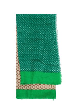 Złożony szalik z zielonym wzorem diamentów na górze i beżową tkaniną z małymi czerwonymi krzyżykami pod spodem, oba z zielonymi frędzlami na krawędziach.
