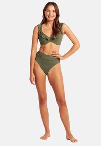 Olivengrünes Bikini-Set mit einem gerafften, tief ausgeschnittenen Oberteil mit verstellbaren Trägern und hochgeschnittenen Unterteilen mit Wickeldesign. Glatte Textur.