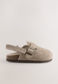 Sabot en daim beige à enfiler avec sangle à boucle réglable et talon ouvert sur une semelle plate texturée.