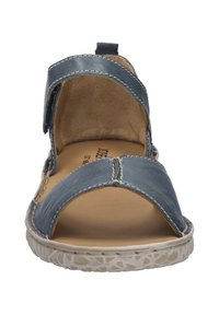 Sininen nahkasandaali, jossa on avonaiset varpaat ja kaksi säädettävää hihnaa, ominaisuutena tikkausyksityiskohdat ja teksturoitu vaaleanvärinen pohja.