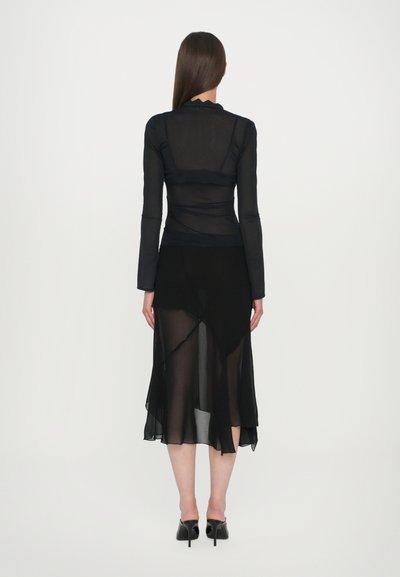Black transparent long-sleeve top with fitted design, paired with a flowing black asymmetrical skirt made of sheer material. High heels included.