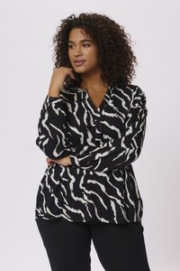 Blouse noire à manches longues avec un motif ondulé blanc, dotée d'un décolleté en V et de boutons, fabriquée à partir d'un tissu lisse avec une coupe décontractée.