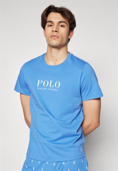 T-shirt de algodão azul claro com decote redondo, apresentando o texto branco "POLO RALPH LAUREN". Mangas curtas e um corte regular.