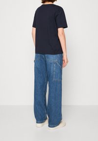 Donkerblauw katoenen t-shirt met een eenvoudige ronde hals, gecombineerd met wijde denim cargo pants met meerdere zakken en contrasterende stiksels.